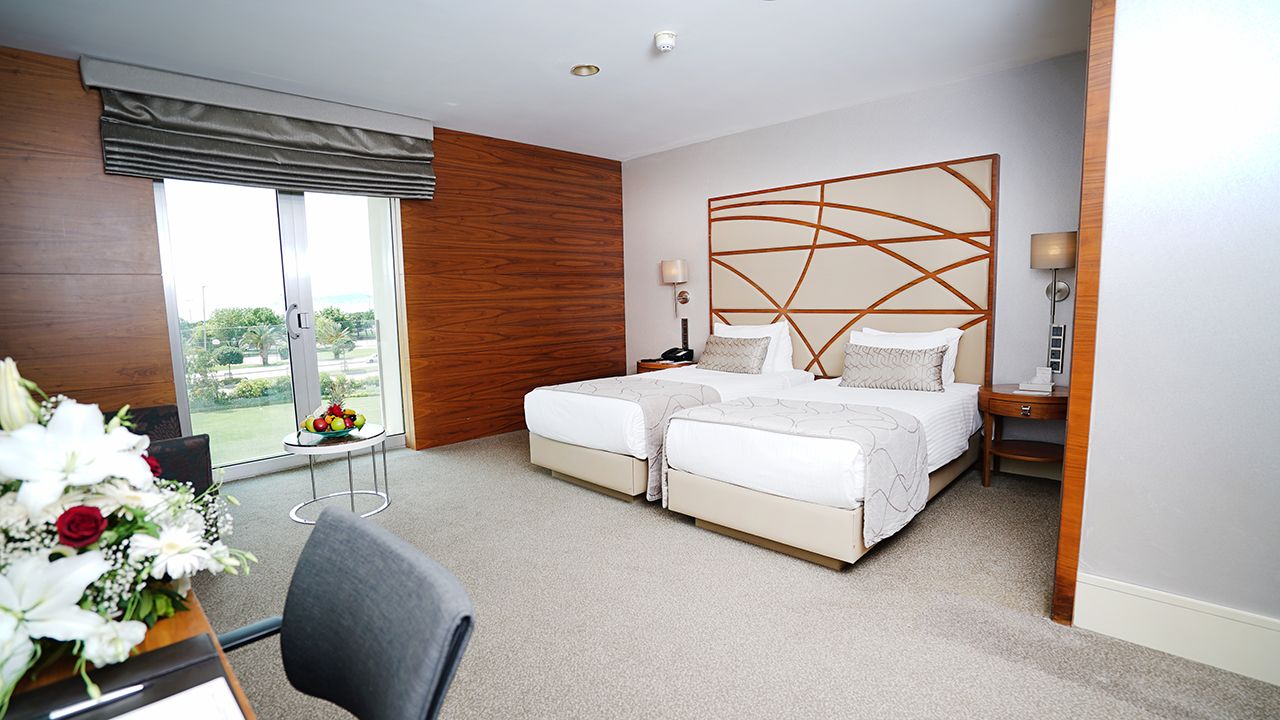 A hotel room with two beds, a large window, and a floral arrangement.